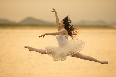 woman in white ballerina dress jumping near body of water thumbnail