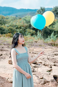 Woman Wearing Blue Dress Holding Balloons thumbnail
