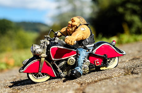 selective focus photo of man in white shirt ride on red and black cruiser motorcycle scale model thumbnail