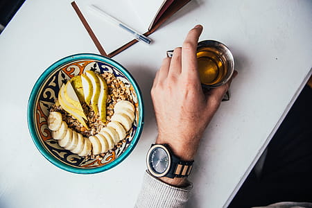 Tea mug held in a male hand with granola in a plate on the table thumbnail