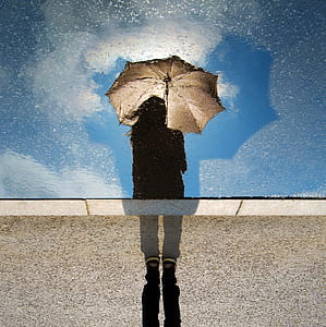 woman standing with umbrella during cloudy day thumbnail