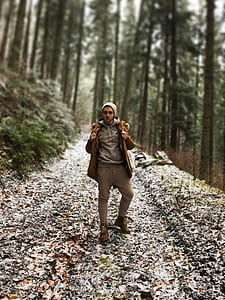 man standing on trail between tree thumbnail