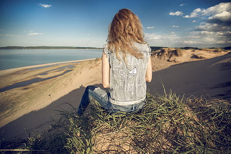 woman sitting on rock looking at the seashore thumbnail