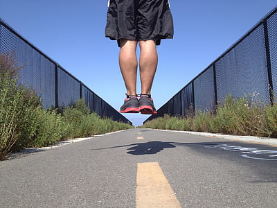 man jumping over gray road thumbnail