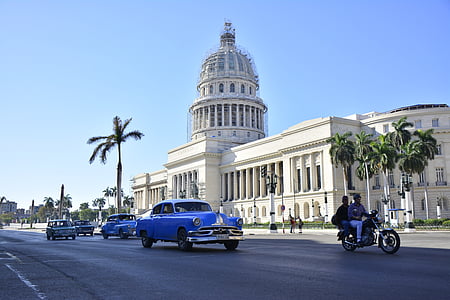 classic blue coupe on road near white concrete building at daytime thumbnail