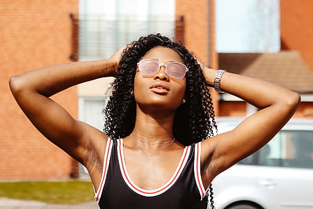 woman wearing black, white, and red tank top while both hands holding the back of her head thumbnail