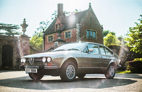 gray Alfa Romeo coupe parked near brown house thumbnail