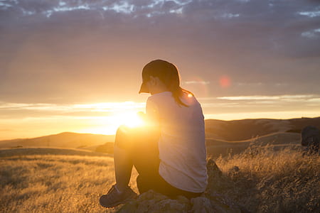 man sitting on stone during golden hour thumbnail