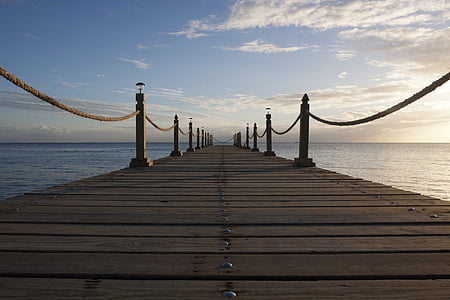 brown wooden pier facing ocean under blue sky thumbnail
