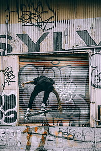 person on air skateboarding near gray, black, and brown metal roll-up door at daytime thumbnail