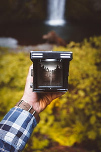 person hand's holding camera displaying waterfall photo thumbnail
