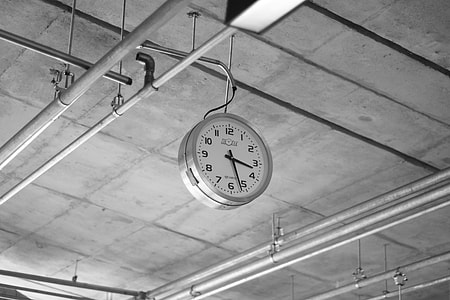 round grey and white framed analog clock hanging on pipe thumbnail