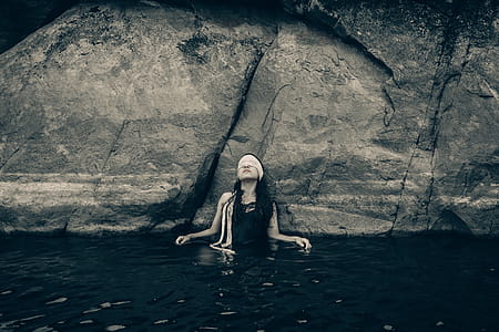Woman in Blindfold Wearing Black Top on Body of Water While Leaning on a Rock thumbnail