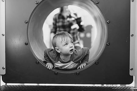 grayscale photo of boy lying on tunnel thumbnail