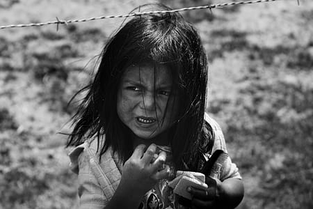 grayscale photography of girl standing under steel barbed wire thumbnail