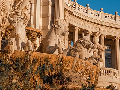 white concrete bull and man statues beside concrete building at daytime thumbnail