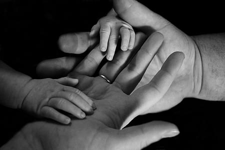 grayscale photography of baby's hands on human hands thumbnail