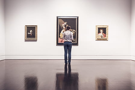 woman standing in front of three paintings mounted on wall in well lit room thumbnail