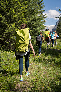 woman with green backpack walking on grass pathway thumbnail