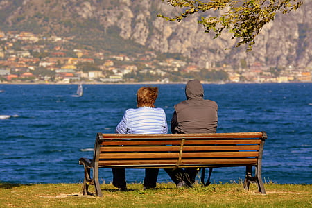 man and woman sitting near calm body of water thumbnail