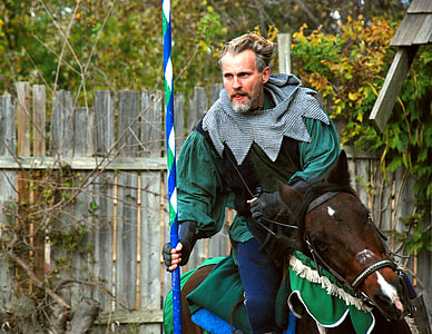 knight riding on brown horse holding blue and white stick thumbnail
