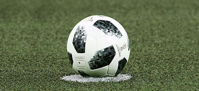 white and black soccer ball on grass field thumbnail