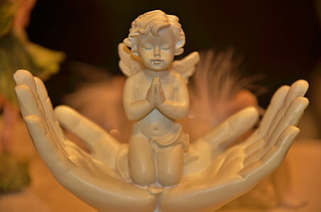 close-up photography of cherub praying on hands ceramic figurine thumbnail
