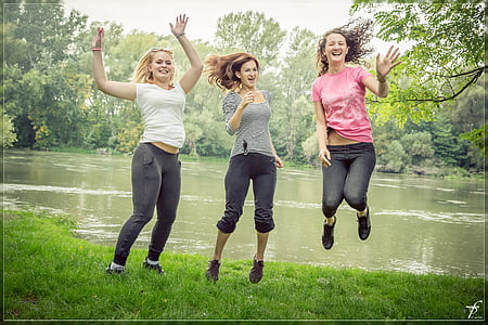 three woman jumping beside body of water thumbnail
