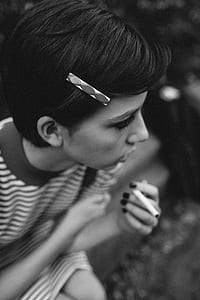 grayscale photography of woman holding cigarette stick thumbnail