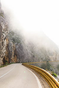 Photography of Road Near Foggy Mountain thumbnail