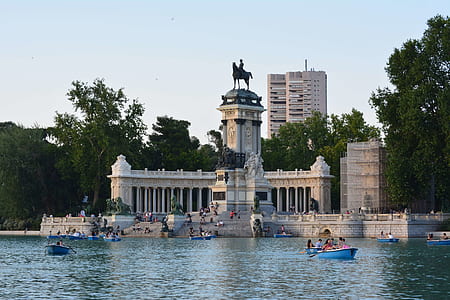 people riding boat on body of water in front of concrete statue thumbnail