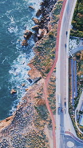 aerial view of highway near body of water thumbnail