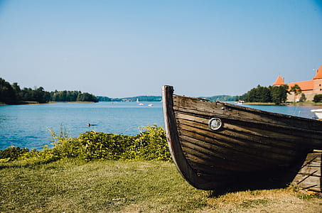 brown wooden canoe near body of water during daytime thumbnail