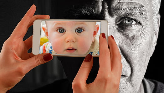 person holding white smartphone with baby's face wallpaper thumbnail