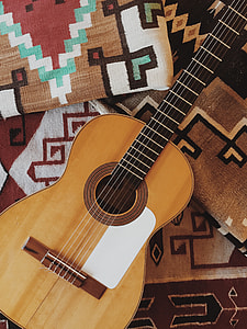 person taking photo of brown acoustic guitar thumbnail