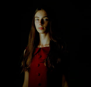 woman wearing red dress looking straight in dark lit room thumbnail