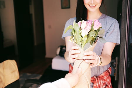 woman in gray shirt holding bouquet of pink petaled flower thumbnail