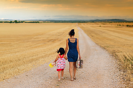 woman and girl in assorted-color sleeveless dresses walking on gray sand thumbnail