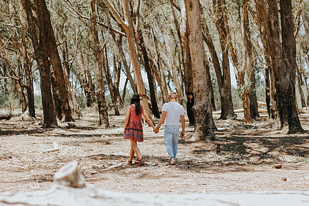 man and woman walking near trees at daytime thumbnail