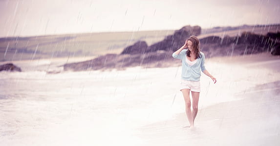 woman standing on beach shore while raining thumbnail