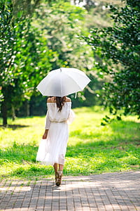 woman walking on brick pavement under umbrella during day thumbnail