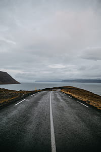 photo of gray concrete road with body of water during daytime thumbnail