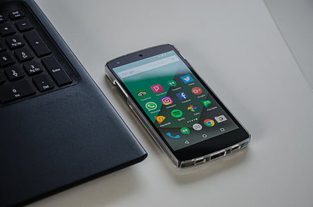 turned on smartphone beside laptop on white surface thumbnail