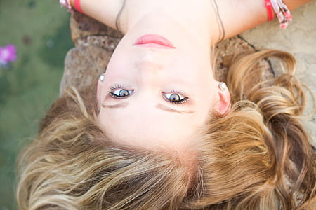 woman with blonde hair lying on rock at daytime thumbnail