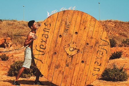 man pushing round brown wooden board during daytime thumbnail