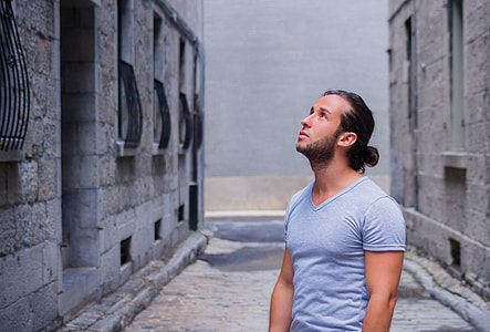 person in gray V-neck T-shirt standing near gray concrete buildings thumbnail