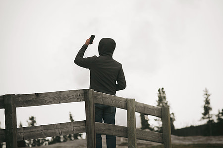 man standing on platform holding his phone thumbnail