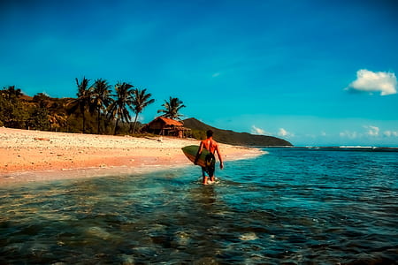 man carrying surfboard on beach thumbnail