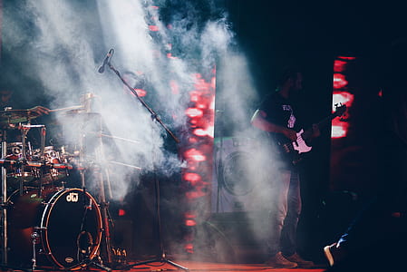 photo of man holding electric guitar near drum set thumbnail