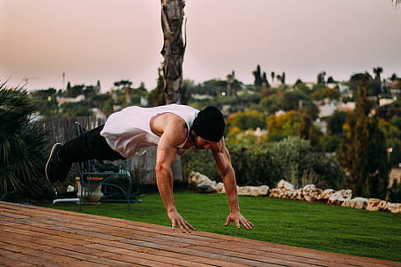 man wearing white tank top doing jumping push up during daytime thumbnail